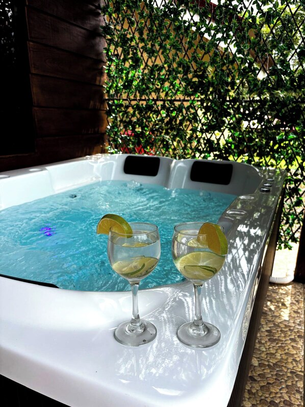 A hot tub with two glasses of a clear liquid, possibly a beverage, with lime slices. - Cozy 2-bedroom cabin in charming Provincia de Alajuela with AC (Provincia de Alajuela)