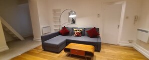 A modern living room with a grey sectional sofa, a wooden coffee table, and a floor lamp.