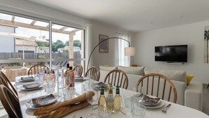 Un coin repas avec une table dressée pour quatre personnes, des chaises, un téléviseur et une vue sur l’extérieur.