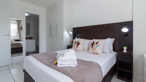 Een verzorgde slaapkamer met een groot bed, nachtkastjes en een spiegel.