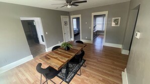 A dining area with a wooden table, black chairs, a ceiling fan, and a potted plant.