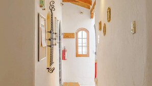 A corridor with a tiled floor, wooden beams, a window, and a fire extinguisher. - Casa Aimee - Suite B · Casa Aimee, High-up Suite (Mexico City)