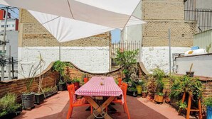 A rooftop patio with a table and chairs, surrounded by potted plants and a white umbrella. - Casa Aimee - Suite B · Casa Aimee, High-up Suite (Mexico City)