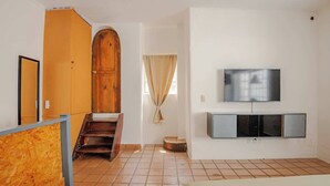 A room with a wooden wardrobe, a TV mounted on the wall, and a bed. - Casa Aimee - Suite B · Casa Aimee, High-up Suite (Mexico City)