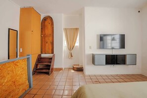 A room with a wooden wardrobe, a television on the wall, and a tiled floor.