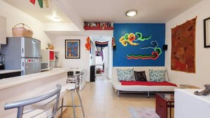 Un salon moderne avec un canapé, un coin repas doté d’un bar, et une cuisine équipée d’un réfrigérateur et d’un four à micro-ondes.