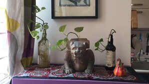 Une pièce avec un meuble violet, une œuvre d’art encadrée, une sculpture décorative et une plante.