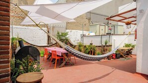 Un patio con una hamaca, asientos de exterior y plantas en macetas.