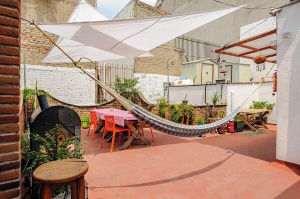 Un patio con una hamaca, asientos de exterior y plantas en macetas.