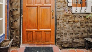 A wooden door with a wrought iron gate, a welcome mat, and a lantern above the door.