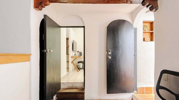 A hallway with a tiled floor, a wooden bench, and a door leading to another room.