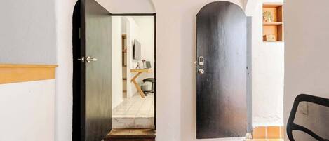 A hallway with a tiled floor, a wooden bench, and a door leading to another room.