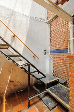 A metal staircase with a handrail leading to a brick wall.