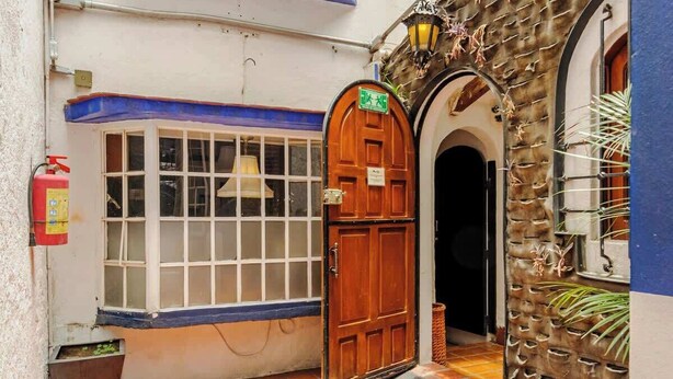 Un estrecho callejón con suelo de baldosas, una puerta de madera y un extintor en la pared.