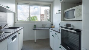 Eine moderne Küche mit weißen Schränken, einem Bosch-Backofen, einer Mikrowelle und einem Fenster mit Blick auf Gebäude.