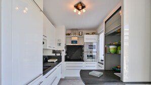 A modern kitchen with white cabinets, a black countertop, and a stainless steel refrigerator.