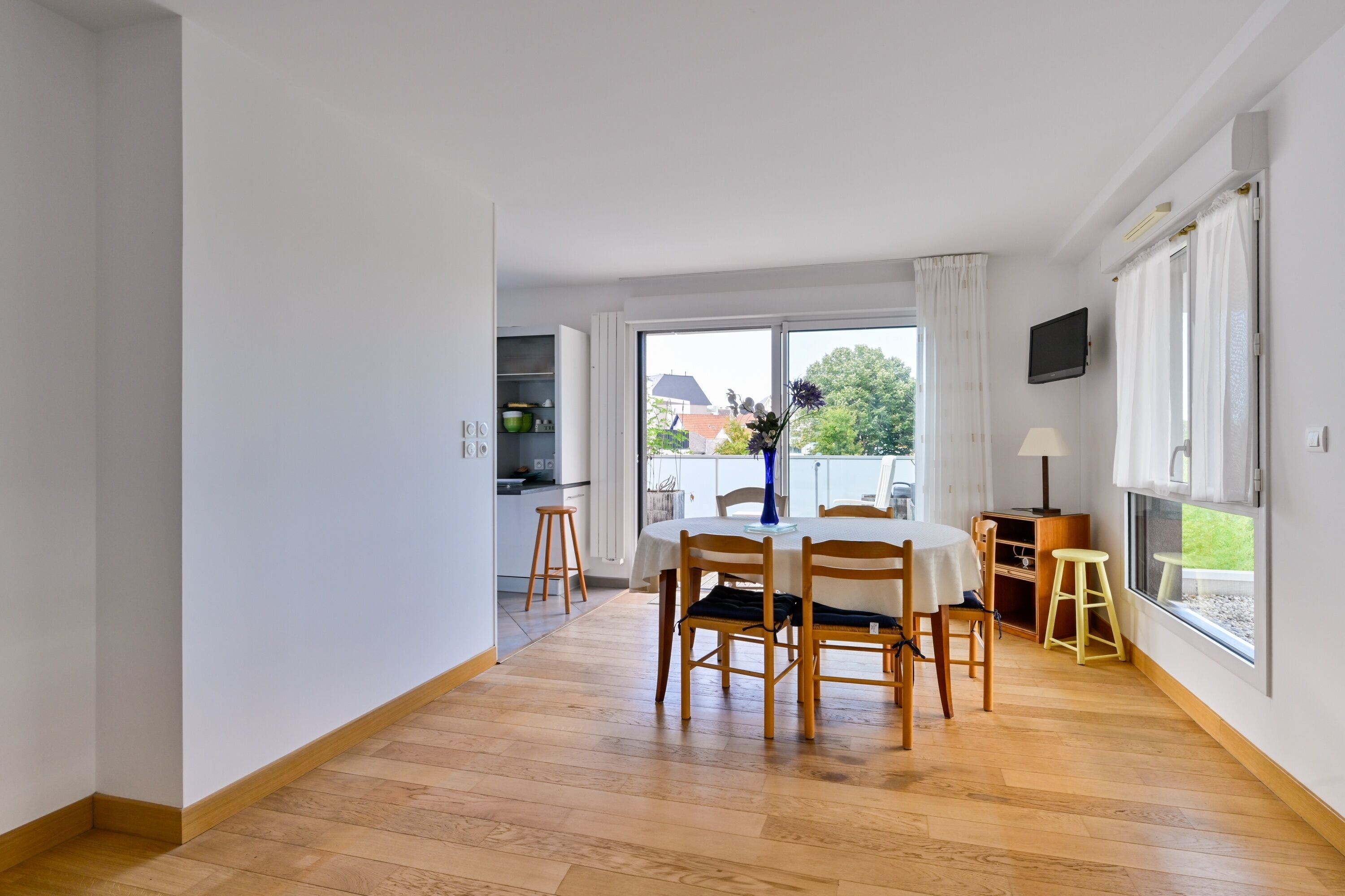 A spacious room with a dining area, a kitchen, and a large window with a view of the outdoors.