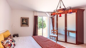 A bedroom with a bed, a chair, a desk, and a wardrobe.