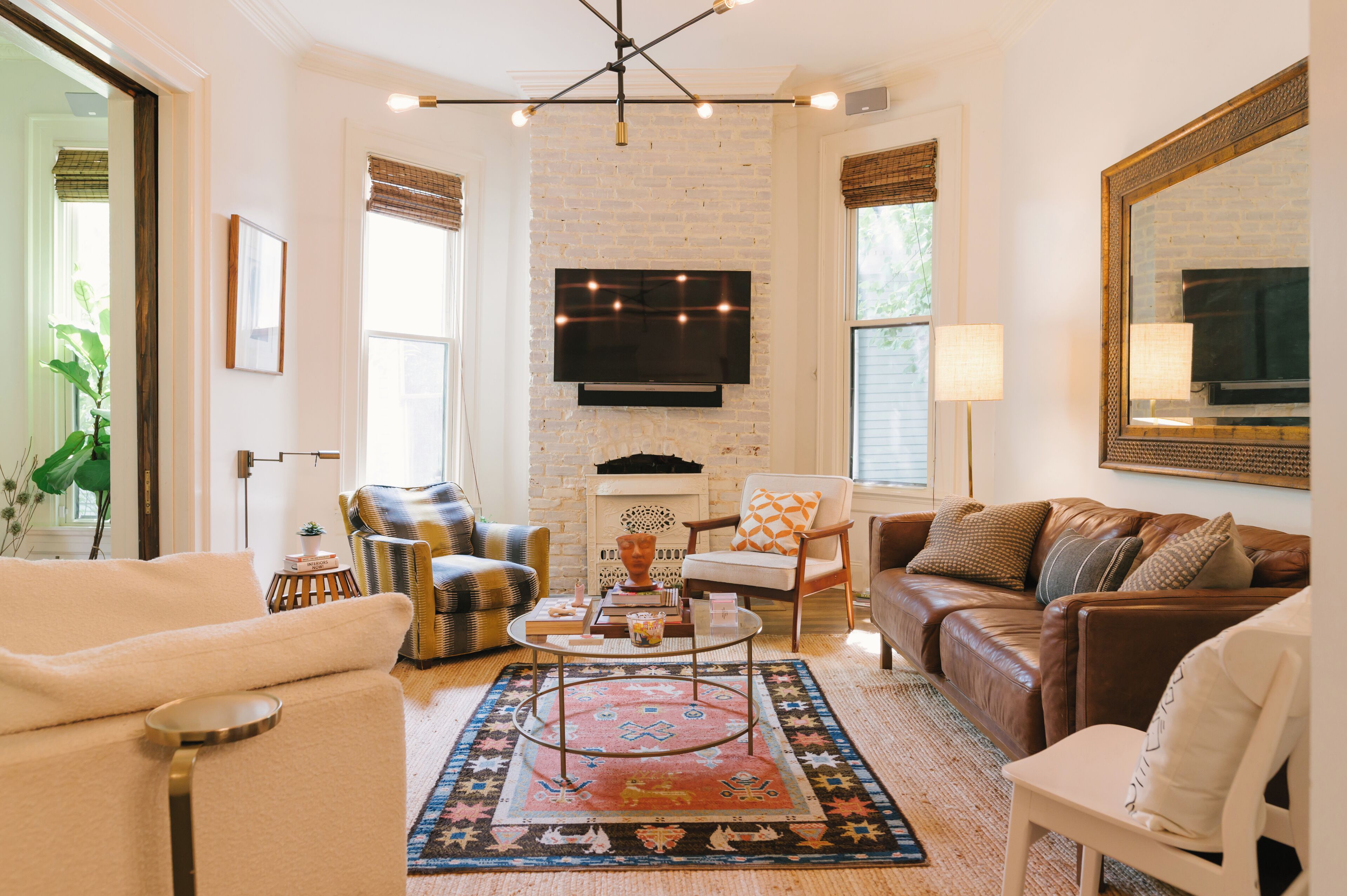 A living room with a fireplace, leather sofas, a coffee table, and a TV mounted on the wall.