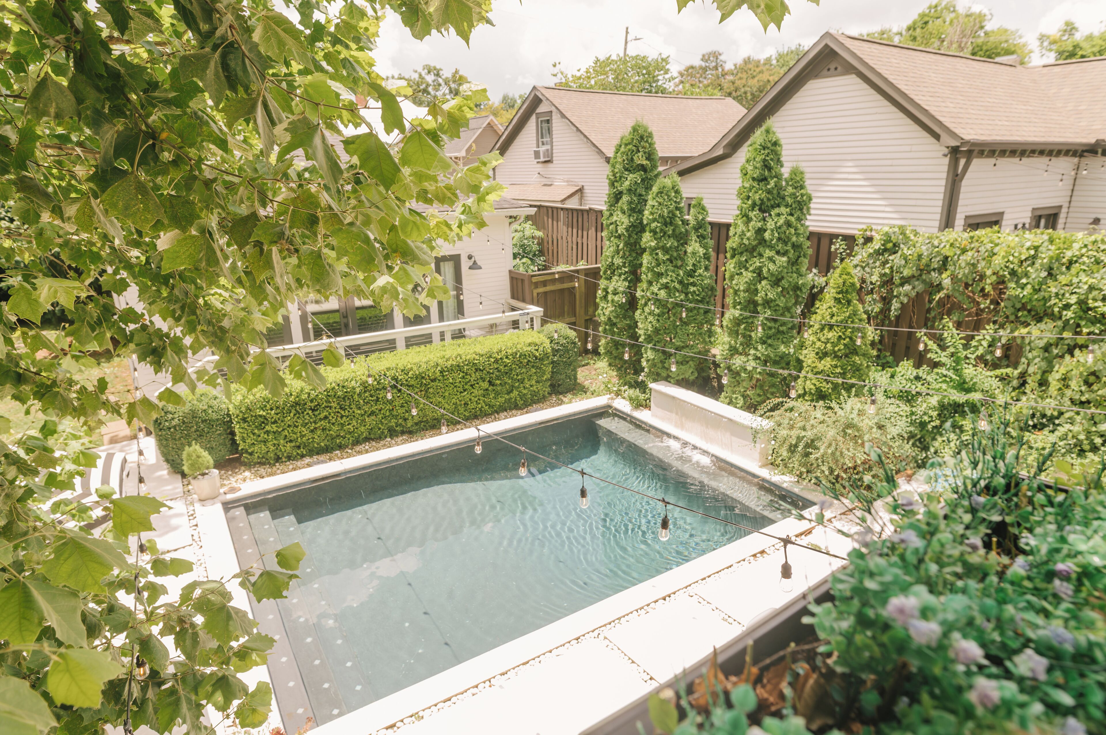Una piscina rodeada de vegetación y una terraza de madera.