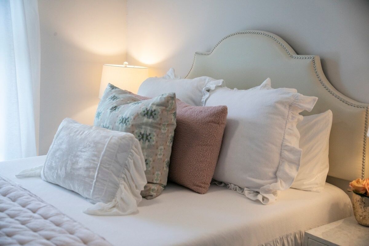 A neatly made bed with multiple pillows and a headboard with a chain detail.