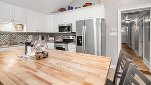 Une cuisine moderne avec des meubles blancs, des appareils en acier inoxydable et une table à manger en bois.