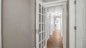 Un couloir avec des portes blanches et un plancher en bois.