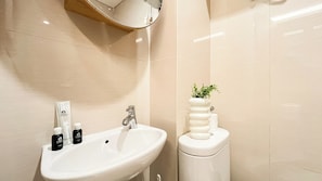 Een badkamer met een wit wastafelmeubel, een spiegel, een toilet en een kleine potplant.