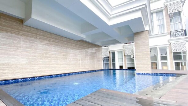 An indoor swimming pool with a wooden deck, tiled walls, and a modern architectural design. - Quiet And Strategic Studio Loft At Apple 1 Condovilla Apartment (Jakarta)