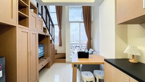 A modern kitchen with wooden cabinets, a black countertop, and a window with curtains. - Quiet And Strategic Studio Loft At Apple 1 Condovilla Apartment (Jakarta)