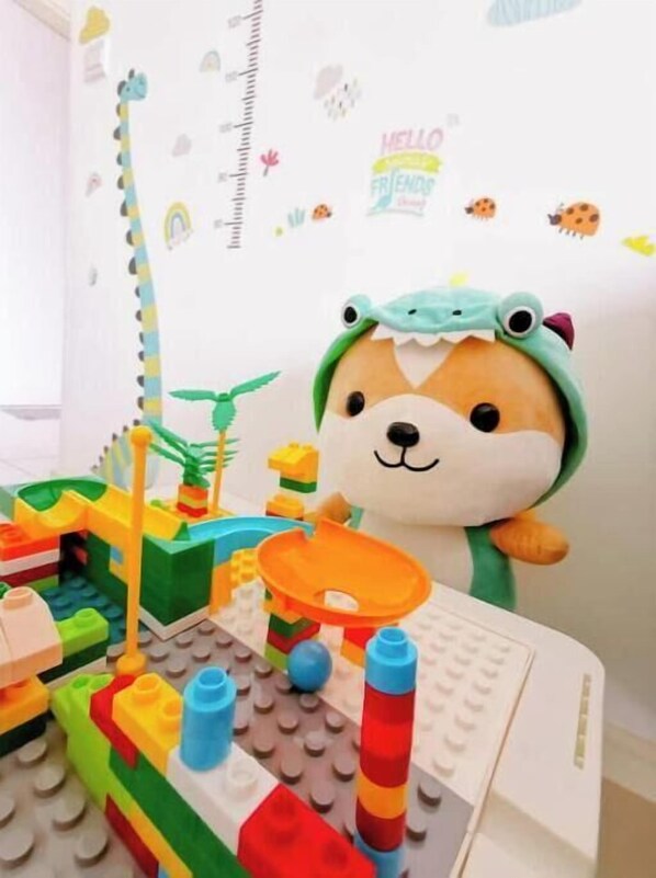 Un espace de jeux pour enfants avec un ensemble de construction LEGO, un animal en peluche et des décorations murales.