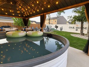 Un área de jacuzzi al aire libre con techo cubierto, sillas de descanso y cerco de madera identificado como 'The Oak House'.