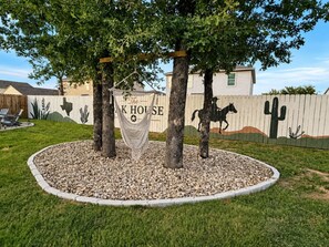 A fenced yard with a hammock, trees, and a horse statue.