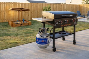 Ein mobiler Blackstone-Grill mit Propangasflasche auf einer Beton-Terrasse.