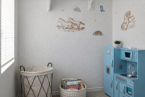 Une chambre d’enfant avec un berceau, un coffre à jouets et une armoire bleue avec un lavabo.