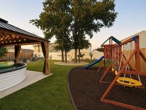 A backyard with a hot tub, a swing set, and a covered patio area. - 5bd/3ba, Cowboy Pool, Playground, Near Granbury (Tolar)