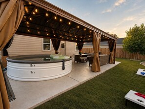 A covered outdoor patio with a hot tub, seating area, and string lights. - 5bd/3ba, Cowboy Pool, Playground, Near Granbury (Tolar)