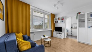 A modern living room with a sofa, a TV, and a dining area. - Downtown Apt - Top Location, Metro nearby (Warszawa)