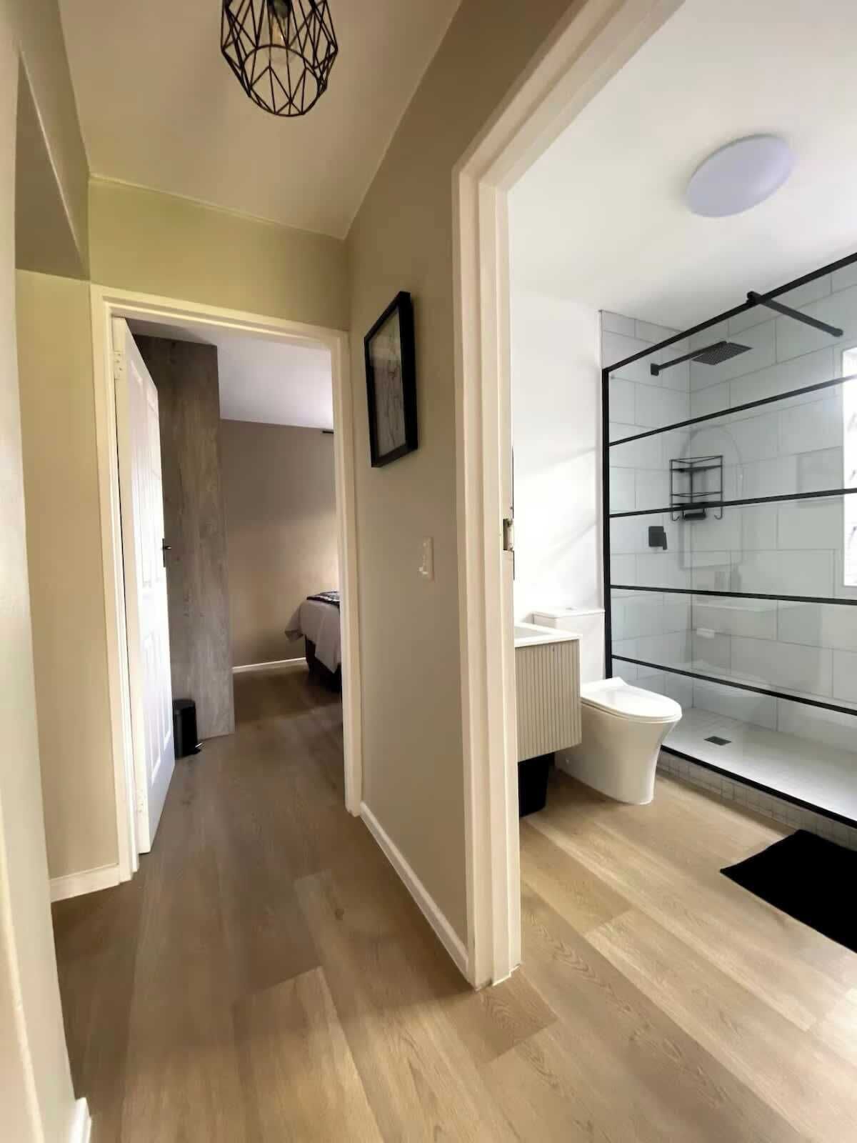 A modern bathroom with a glass shower enclosure, a toilet, and a sink.