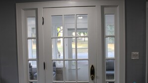 A white door with glass panels, a doormat, and a small table with a water bottle beside it. - Spacious, Fully Remodel 4-bedroom house 2.5 bathroom in charming Carthage (Carthage)