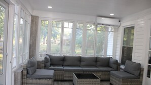 A sunroom with a sectional sofa, two side tables, and large windows offering a view of the outdoors. - Spacious, Fully Remodel 4-bedroom house 2.5 bathroom in charming Carthage (Carthage)