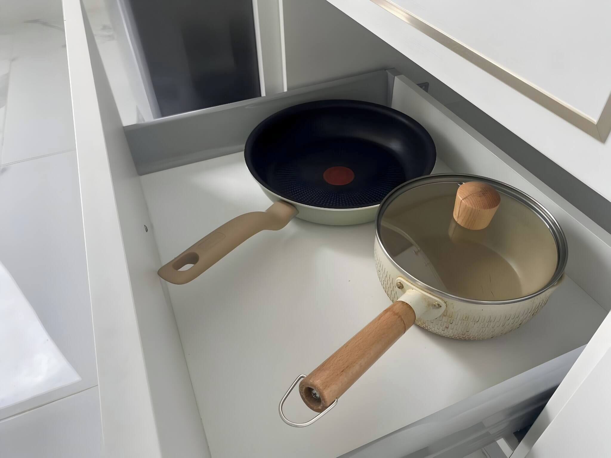 A kitchen drawer containing a frying pan and a pot.