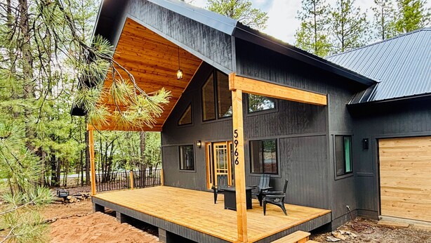 Una casa moderna con terraza de madera, ventanas amplias y un garaje.