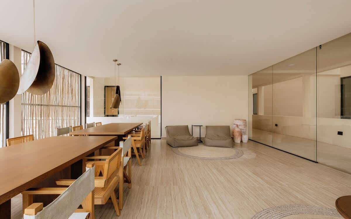 Un intérieur moderne avec une table à manger en bois, des chaises, un canapé et une cloison en verre.