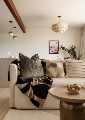 A living room with a sofa, a round table, a hanging light fixture, and a framed picture on the wall.