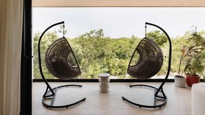 A balcony with two wicker chairs and a small table, overlooking a lush green landscape. - Soluna Samsara Jungle Retreat Beach Club Access (Tulum)