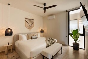 Un dormitorio con cama, mesitas de noche, ventilador de techo, luces empotradas en la pared, una planta en maceta y una puerta corrediza de vidrio.