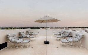 A rooftop terrace with outdoor seating and a central umbrella.