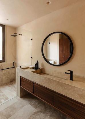 A modern bathroom with a large mirror, a shower, and a vanity with a sink.