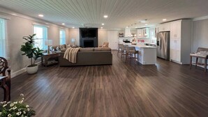 Ein geräumiger Wohnbereich mit großzügigem Sofa, Esstisch und einer Küchenzeile mit modernen Geräten.